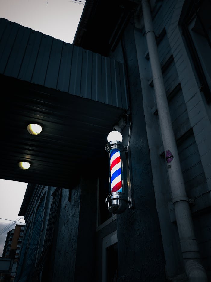 Barbershop pole on a building facade in Ukraine's urban setting at night.