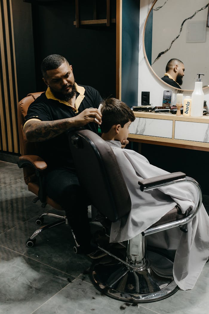 A skilled barber gives a young boy a stylish haircut in a contemporary barbershop setting.